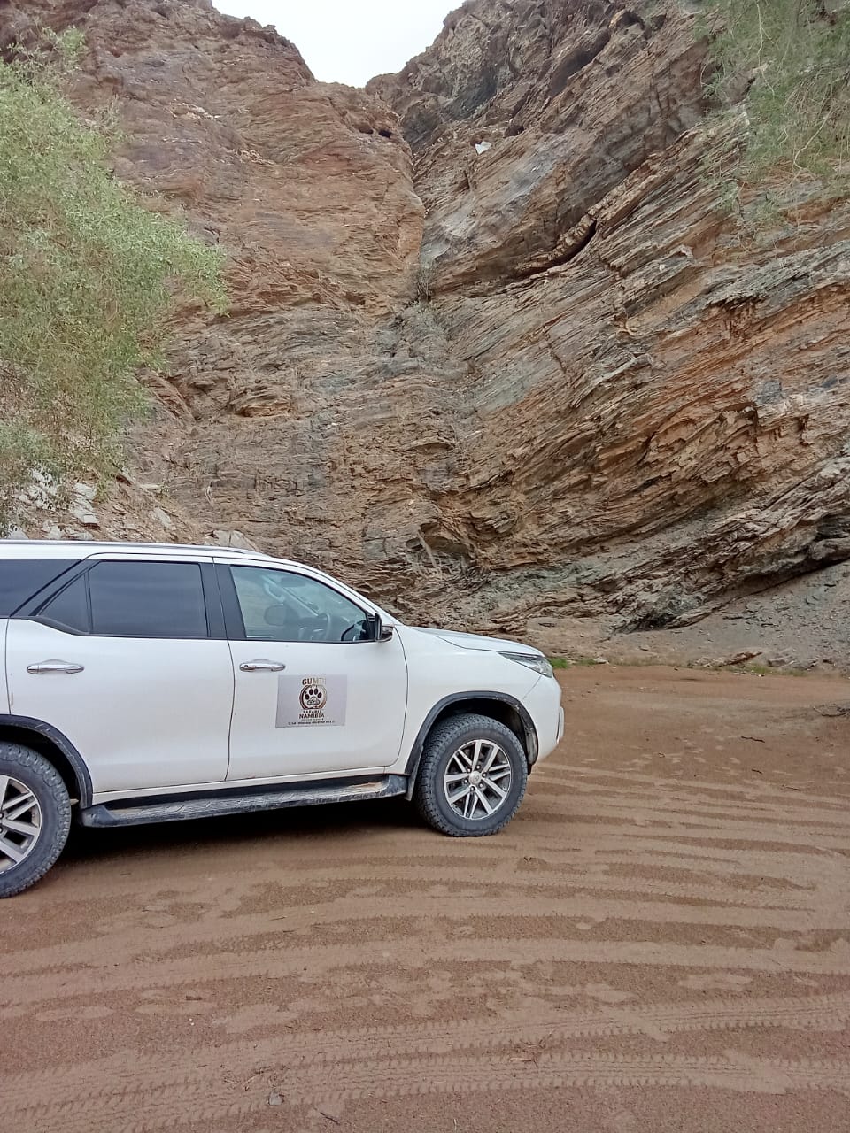 The Gumbi Safaris vehicle beside folded canyon rock